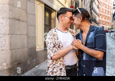 Eine zärtliche Szene, in der zwei Männer in einer sonnendurchfluteten Straße gefangen werden, die Zuneigung und Wärme in einer ungezwungenen urbanen Umgebung zeigt. Stockfoto
