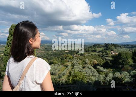 Eine Frau blickt über die üppigen, sanften Hügel der Toskana, mit Weinbergen und Olivenhainen, die sich in Richtung San Gimignano erstrecken Stockfoto