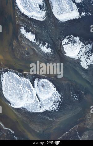 Ein atemberaubendes Luftbild fängt Islands Südküste ein, wo schneebedeckte Landformationen einen wunderschönen Kontrast zu dunklen Gewässern bilden und n enthüllen Stockfoto