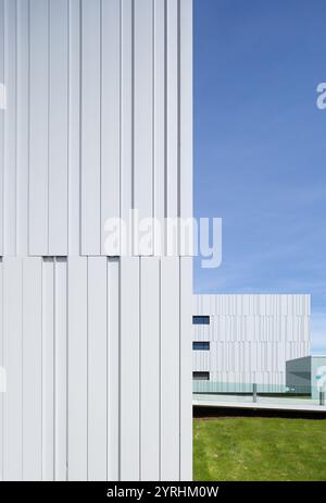 Ein modernes Krankenhausgebäude mit schlanker, weißer Vertäfelung und minimalistischer Architektur, das sich vor einem klaren blauen Himmel befindet und moderne Gesundheitsfürsorge widerspiegelt Stockfoto