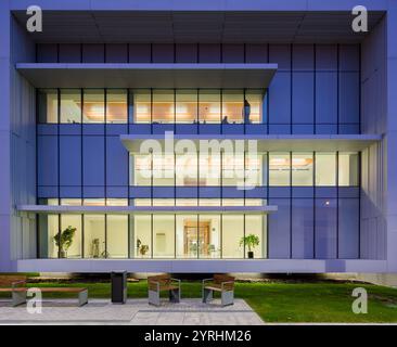 Captivating image of a hospital center's modern exterior It features a sleek glass facade, warm interior lighting, and a serene green environment with Stockfoto