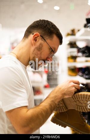 Ein Mann schaut sich Schuhe und Kleidung in einem Laden an Stockfoto