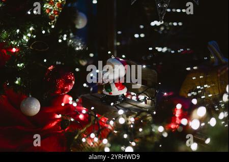 Ein weihnachtsbaum mit einem weihnachtsmann, der auf einer Bank sitzt. Die Bank ist von Lichtern umgeben Stockfoto