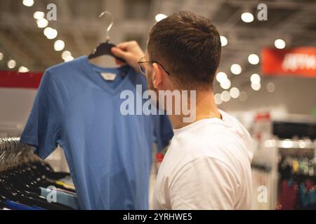 Ein Mann schaut sich Schuhe und Kleidung in einem Laden an Stockfoto