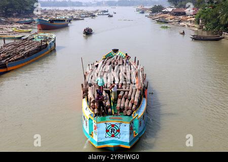 Swarupkathi, Pirojpur, Bangladesch. Dezember 2024. Händler kaufen Holz auf dem größten schwimmenden Holzmarkt in Bangladesch in Swarupkathi upazila im Bezirk Pirojpur und transportieren es in großen Booten. Der Markt bietet eine große Auswahl an einheimischen Hölzern, darunter Mahagoni, Champagner und raintree. Händler aus dem ganzen Land kaufen auf diesem Upazila-Markt Holz im Wert von einem Lakh-Dollar. Diese Hölzer werden dann auf verschiedenen Wegen durch das ganze Land transportiert, darunter LKW, Starts und Frachtschiffe. Tausende von Menschen in Swarupkathi sind tief in diese blühende Holzart verwickelt Stockfoto