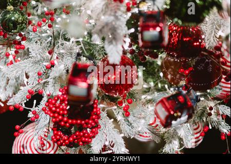 Ein wunderschön geschmückter Weihnachtsbaum mit einem Zugschmuck. Der Zug ist rot-weiß und das Herzstück des Baumes. Der Baum ist mit verschiedenen Ornamenten gefüllt Stockfoto