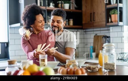 Glückliches afroamerikanisches Paar, das zusammen in der Küche frühstückt Stockfoto