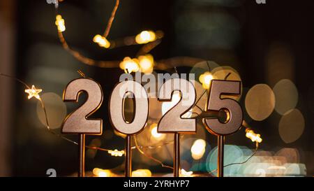 Frohe Neujahrsfeier 2025 mit festlichen Lichtern bei Nacht. Goldene Kerzen 2025 mit Bokeh-Sternen-Lichtern Stockfoto