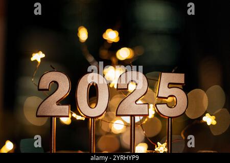 Goldene Kerzen, festlich 2025 Uhr nachts mit urbanem Bokeh mit Lichtersternen. „Happy New Year 2025“-Karten Stockfoto