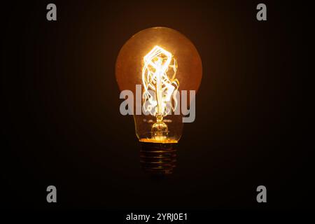 Kreative Glühlampe mit Glühfaden leuchtet im Dunkeln. Strom und Energie, kreative Idee. Anders denken, Konzept. Stockfoto