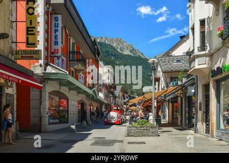 Blick auf die Rue Joseph Vallot im Zentrum der Bergstadt, mit einem Touristenzug und der Aiguilles Rouges im Sommer, Chamonix, Frankreich Stockfoto