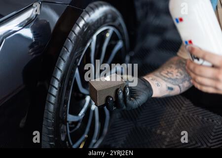Professioneller Mann, der Auto und Räder in der Garage wäscht. Detaillierung. Reifenpflege Stockfoto