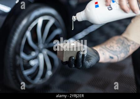 Professioneller Mann, der Auto und Räder in der Garage wäscht. Detaillierung. Reifenpflege Stockfoto