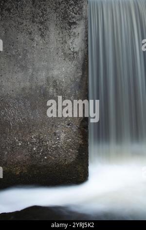 Lange Exposition von Wasser, das über einen Wasserdamm fließt. Stockfoto