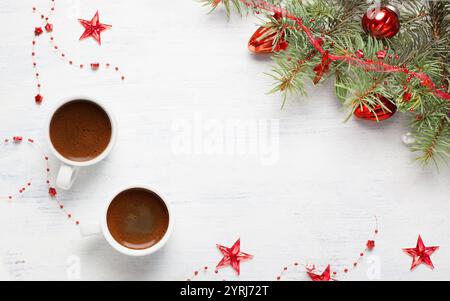 Zwei Tassen Kaffee und rote Weihnachtsdekoration auf einem alten, schäbigen weißen Holztisch. Stockfoto