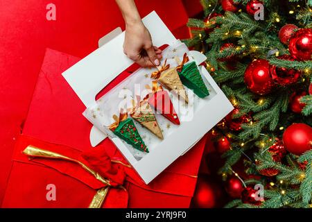 Draufsicht. Ein Set Käsekuchen-Desserts wird von der Hand eines Mädchens aus einem offenen Paket genommen. Stockfoto