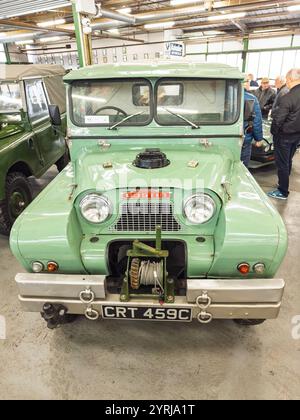 1965 Vintage hellgrüner Austin Zigeunerwagen mit Winde auf einer Oldtimer-Auktion im Innenbereich mit anderen Fahrzeugen und Besuchern im Hintergrund Stockfoto