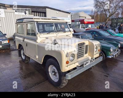 Klassische cremefarbene Land Rover Series III parkte bei einer Fahrzeugauktion in northumberland unter modernen Autos Stockfoto