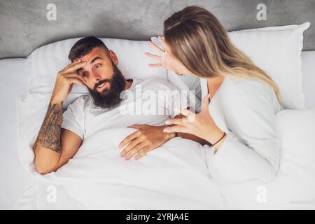 Das Paar liegt im Bett und streitet sich. Die Frau ist wütend auf den Mann. Stockfoto