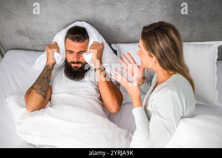 Das Paar liegt im Bett und streitet sich. Die Frau ist wütend auf den Mann. Stockfoto