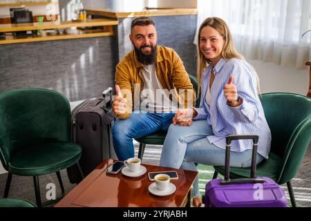 Das junge glückliche Paar geht in den Urlaub. Touristen sitzen in der Hotellobby und trinken Kaffee. Stockfoto