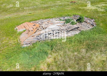 Ein Haufen Holz und Schutt liegt auf einem grasbewachsenen Feld. Der Stapel ist groß und hat viel Holz. Das Gras ist grün und der Haufen befindet sich in der Mitte des Stockfoto