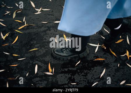 Ein Mädchen läuft auf nassem Asphalt mit herabfallenden Blättern drauf. Hochwertige Fotos Stockfoto