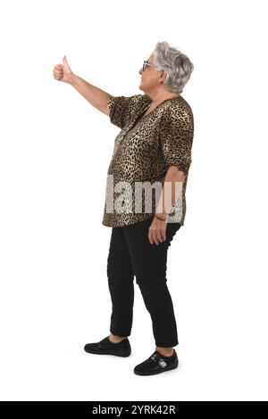 Seitenansicht eines Porträts einer älteren Frau in voller Länge mit Daumen nach oben auf weißem Hintergrund Stockfoto