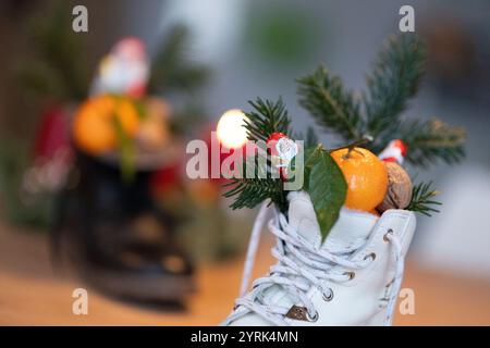Stuttgart, Deutschland. Dezember 2024. Stiefel gefüllt mit Zitrusfrüchten, Walnüssen und Schokolade stehen auf einem Tisch (posierte Szene). Der Nikolaustag am 6. Dezember geht auf die Legende von zwei Bischöfen aus dem 4. Und 6. Jahrhundert zurück, deren karitative Taten und Geschichten die Grundlage der Tradition bildeten. Quelle: Marijan Murat/dpa/Alamy Live News Stockfoto