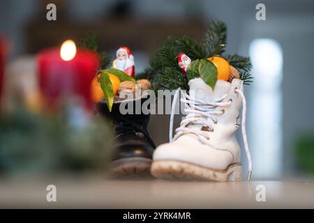 Stuttgart, Deutschland. Dezember 2024. Stiefel gefüllt mit Zitrusfrüchten, Walnüssen und Schokolade stehen auf einem Tisch (posierte Szene). Der Nikolaustag am 6. Dezember geht auf die Legende von zwei Bischöfen aus dem 4. Und 6. Jahrhundert zurück, deren karitative Taten und Geschichten die Grundlage der Tradition bildeten. Quelle: Marijan Murat/dpa/Alamy Live News Stockfoto