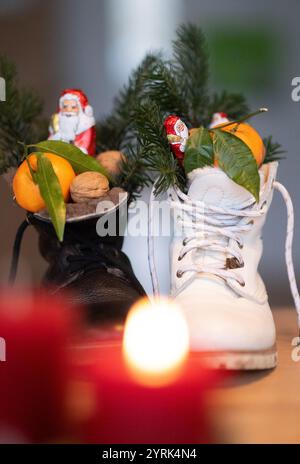 Stuttgart, Deutschland. Dezember 2024. Stiefel gefüllt mit Zitrusfrüchten, Walnüssen und Schokolade stehen auf einem Tisch (posierte Szene). Der Nikolaustag am 6. Dezember geht auf die Legende von zwei Bischöfen aus dem 4. Und 6. Jahrhundert zurück, deren karitative Taten und Geschichten die Grundlage der Tradition bildeten. Quelle: Marijan Murat/dpa/Alamy Live News Stockfoto