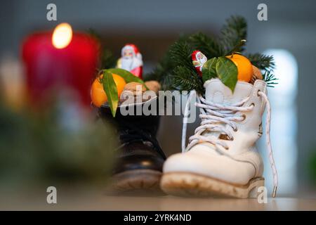 Stuttgart, Deutschland. Dezember 2024. Stiefel gefüllt mit Zitrusfrüchten, Walnüssen und Schokolade stehen auf einem Tisch (posierte Szene). Der Nikolaustag am 6. Dezember geht auf die Legende von zwei Bischöfen aus dem 4. Und 6. Jahrhundert zurück, deren karitative Taten und Geschichten die Grundlage der Tradition bildeten. Quelle: Marijan Murat/dpa/Alamy Live News Stockfoto