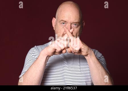 Mann mit Kreuzzeichen und gekreuzten Fingern auf weißem Hintergrund Stockfoto