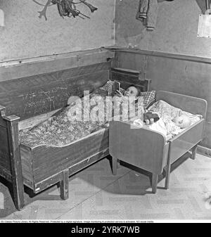 In den 1940er Jahren Eine junge Frau in einem ländlichen Haushalt in Norrbotten Schweden 1949. Sie hat ihr Bett auf einem Küchensofa gemacht, mit ihrem Kind neben ihr. Das Kinderbett hat eine clevere Konstruktion, die sich mit zunehmendem Wachstum verlängern lässt. 1949 Kristoffersson Ref. B56-5 Stockfoto