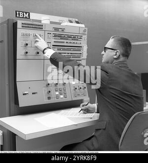 In den 1960er Jahren Innenraum eines Raumes mit Computern und Personen, die mit ihnen umgehen und Informationen registrieren und lesen. Auf einem Schild über dem Mainframe-Computer steht IBM 360. IBM System 360 wurde häufig in der us-amerikanischen Fernsehserie Mad Men gesehen. Foto aufgenommen 1965 Kristoffersson Ref. DY125-3 Stockfoto