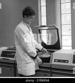 IBM-Mainframe-System 360. Ein Mann in einem Raum, in dem Computergeräte sichtbar sind. Die IBM 2311 Direct Access Storage Facility wurde 1964 für den Einsatz in der gesamten System/360-Computerfamilie eingeführt. Es hat bis zu 7,25 MB auf einem einzigen Wechseldatenträger-Pack gespeichert. Der 2311 wurde mit einer IBM-Standardschnittstelle geliefert, was zu einer ganzen Branche von „Plug-kompatiblen“ Festplattenherstellern wie Control Data Corporation und Memorex führte. Kristoffersson Ref. DY127-12 Stockfoto