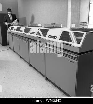 IBM-Mainframe-System 360. Ein Mann in einem Raum, in dem Computergeräte sichtbar sind. Die IBM 2311 Direct Access Storage Facility wurde 1964 für den Einsatz in der gesamten System/360-Computerfamilie eingeführt. Es hat bis zu 7,25 MB auf einem einzigen Wechseldatenträger-Pack gespeichert. Der 2311 wurde mit einer IBM-Standardschnittstelle geliefert, was zu einer ganzen Branche von „Plug-kompatiblen“ Festplattenherstellern wie Control Data Corporation und Memorex führte. Kristoffersson Ref. DY127-2 Stockfoto
