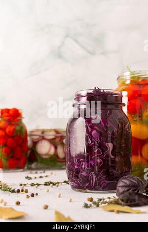 Frischer Rotkohl vergärt in einem Glas mit Gewürzen, wodurch ein gesundes probiotisches Essen entsteht, frisches fermentierendes Gemüse Tomaten und Radieschen Stockfoto