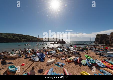 Sommertag in Hope Cove, South Hams, Devon, mit goldenem Sand unter dem Glanz der Sonne, mit Sonnenstrahlen und überfülltem Strand. Stockfoto