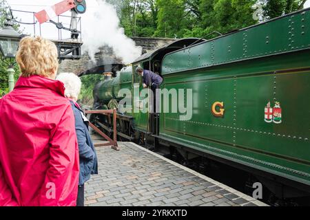 Severn Valley Railway, Arley, Worcestershire, 16-06-2019. Zwei Damen sehen zu, wie eine Dampfeisenbahn (die Bristolian) losfährt und Dampf saust. Stockfoto