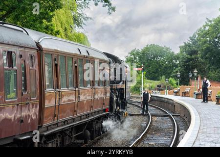 Severn Valley Railway, Arley, Worcestershire, 16-06-2019. Ein alter Dampfzug steigt auf den Bahnsteig an der Arley Station. Constumed Worker steht auf der Stockfoto