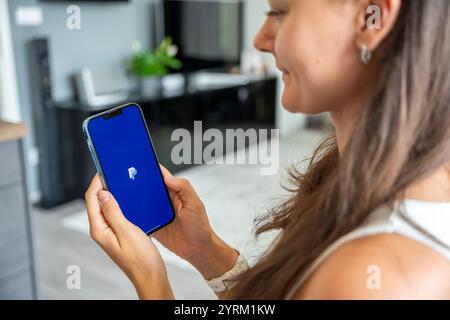 Prag, Tschechische republik - 2. Mai 2024: Frau mit iPhone und Chat-Anwendung PayPal auf dem Bildschirm, mit mobiler Anwendung für Business Home Stockfoto