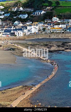 Der öffentliche Damm zwischen St. Michael's Mount und Marazion, der von der steigenden Flut mit Wanderern auf dem Weg Cornwall England bedeckt wird Stockfoto