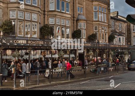 Eine belebte Straßenszene vor dem Bettys Cafe Tea Room, einem mehrstöckigen Gebäude mit großen Fenstern und einer dunklen Markise, die seinen Service zeigt: Kaffee Stockfoto