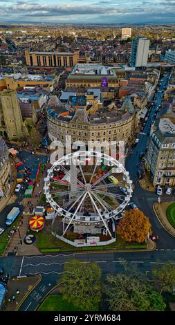 Blick aus der Vogelperspektive auf das Stadtzentrum mit Riesenrad, Weihnachtsmarktstände und umliegende Gebäude. Straßen und Autos sind zu sehen, zusammen mit Bäumen Stockfoto