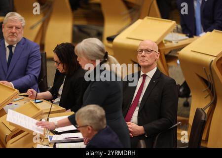 Der erste schottische Minister John Swinney, hört zu, wie Finanzministerin Shona Robison den Entwurf des Haushaltsplans für 2025-26 im schottischen Parlament in Holyrood (Edinburgh) ankündigt. Bilddatum: Mittwoch, 4. Dezember 2024. Stockfoto