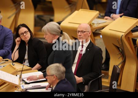 Der erste schottische Minister John Swinney, hört zu, wie Finanzministerin Shona Robison den Entwurf des Haushaltsplans für 2025-26 im schottischen Parlament in Holyrood (Edinburgh) ankündigt. Bilddatum: Mittwoch, 4. Dezember 2024. Stockfoto