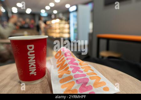 KUALA LUMPUR, MALAYSIA – 28. NOVEMBER 2023: Kaffee in einer Papiertasse, neben einem Donut, im Behälterkonzept Dunkin' Donuts Outlet at am Vormittag Stockfoto