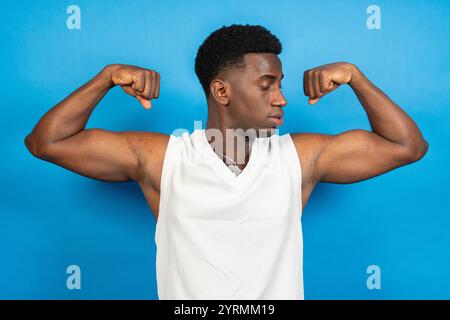 Starker Sportler, der Bizeps biegt, während er vor blauem Hintergrund steht Stockfoto