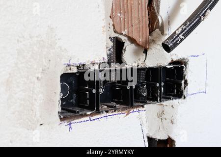 Wellrohre und Elektrokästen, die während eines Renovierungsprojekts in einer Wand installiert werden Stockfoto